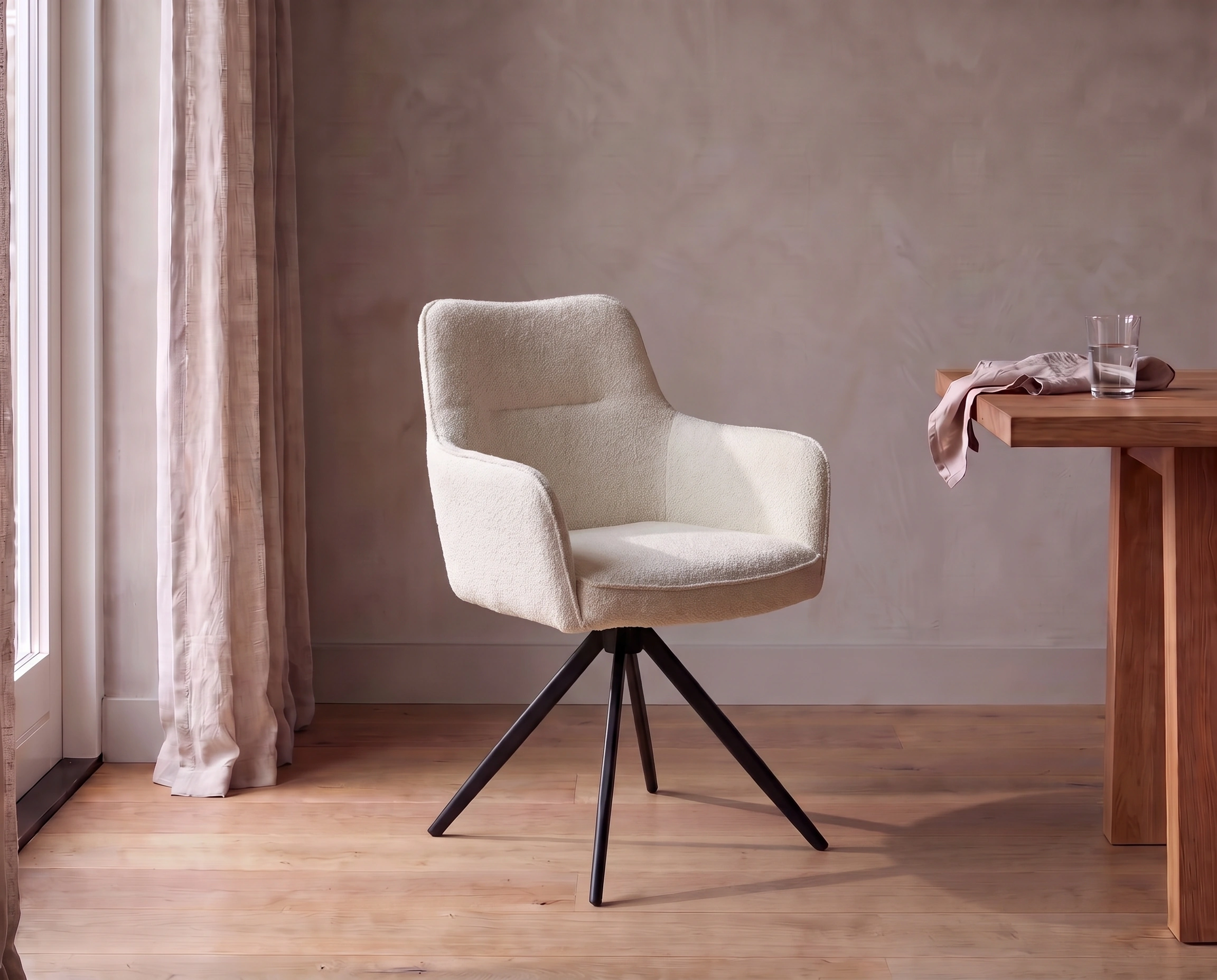 Stoel Lara in off white met armleuningen en zwart onderstel aan een houten eettafel