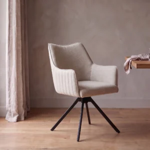 Stoel Nicole in off white met armleuningen en zwart onderstel aan een houten eettafel