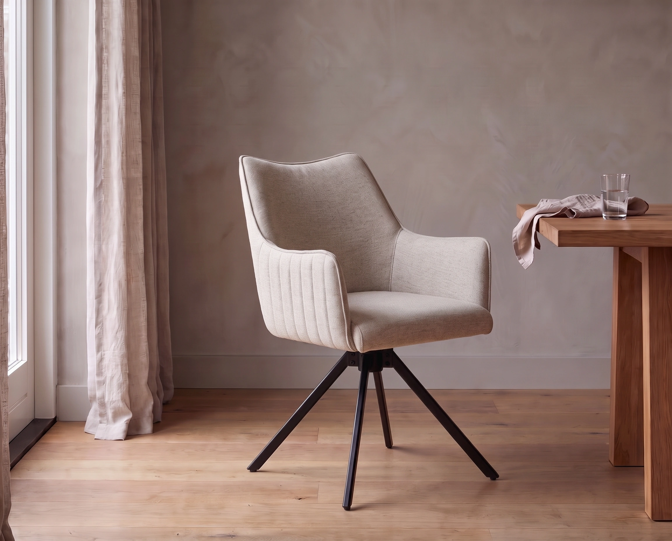 Stoel Nicole in off white met armleuningen en zwart onderstel aan een houten eettafel